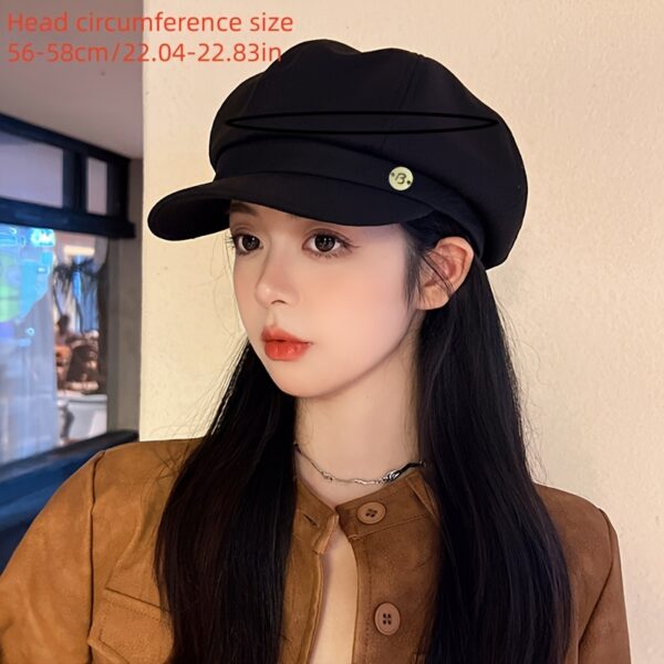 Close up of a black womens wide brim beret with a green button showcasing its texture and structured design