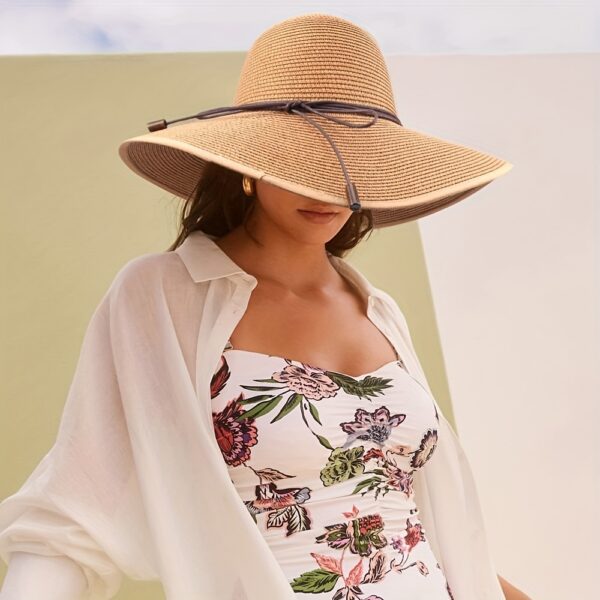 Stylish woman wearing a Newness St. Tropez Wide Brim Straw Hat, showcasing its foldable design and chic appearance.