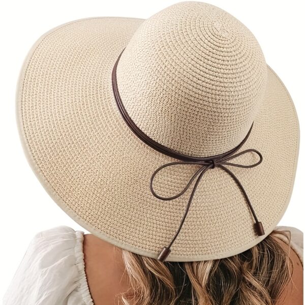 Stylish woman wearing a Newness St. Tropez Wide Brim Straw Hat, showcasing its foldable design and chic appearance.