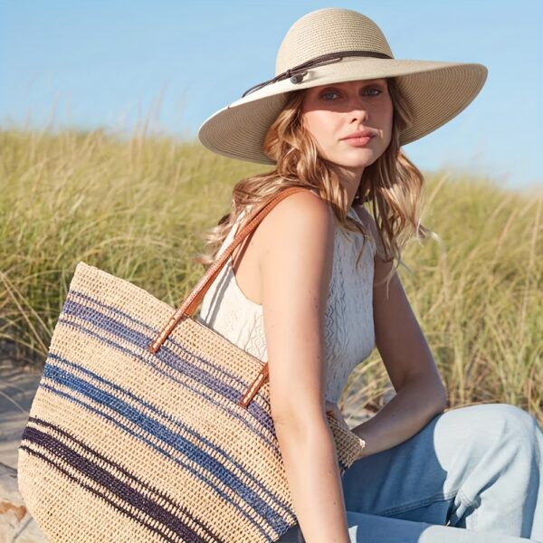 Stylish woman wearing a Newness St. Tropez Wide Brim Straw Hat, showcasing its foldable design and chic appearance.