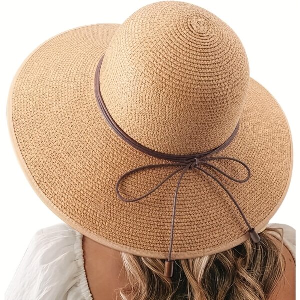 Stylish woman wearing a Newness St. Tropez Wide Brim Straw Hat, showcasing its foldable design and chic appearance.