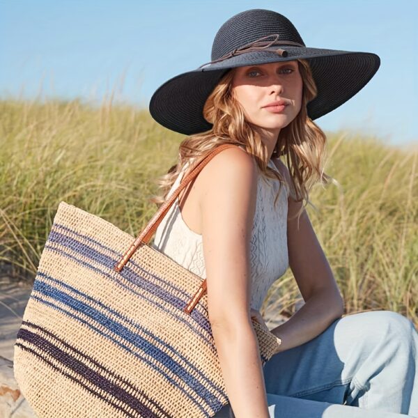 Stylish woman wearing a Newness St. Tropez Wide Brim Straw Hat, showcasing its foldable design and chic appearance.