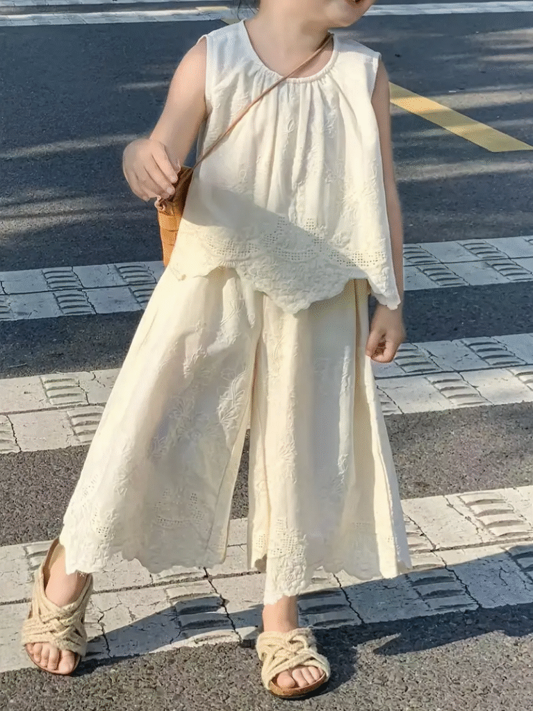 Adorable girl wearing the Newness Summer Breeze Girls Lace Summer Set, a charming 100% cotton outfit perfect for summer. The set features delicate lace detailing and a breathable design for ultimate comfort.