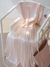 Flatlay of the Newness Bisous Rosé pink pleated midi set showcasing the skirt and top separately and together The set is a beautiful shade of pink and features delicate pleats