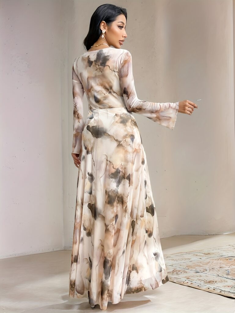 Model wearing a flowing tie-dye maxi dress in shades of blues and purples. The dress features a flattering silhouette and is perfect for weddings, parties, or everyday elegance. Shop the ethereal tie dye maxi dress from Newness.
