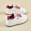 Womens white low top sneakers with red laces showcasing the side profile of the shoe