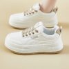 Womens white low top sneakers with red laces showcasing the side profile of the shoe