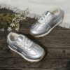 Stylish silvery gray and white low top sneakers for kids featuring a durable TPR sole breathable lining and secure lace up closure Perfect for everyday wear