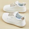 Womens white low top sneakers with red laces showcasing the side profile of the shoe