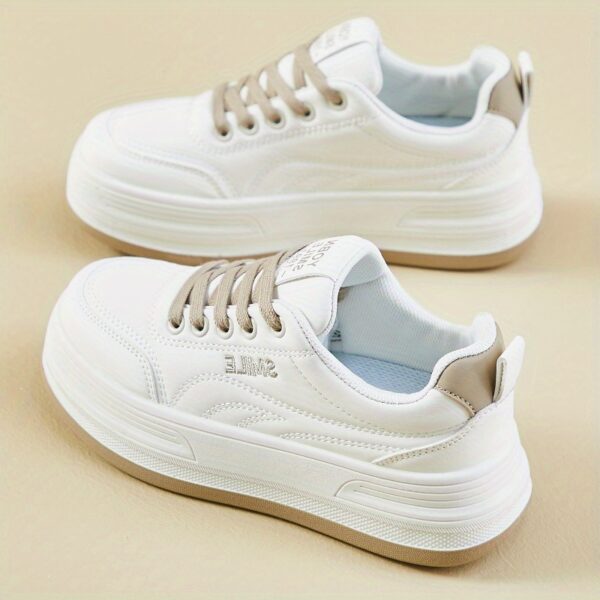 Womens white low top sneakers with red laces showcasing the side profile of the shoe
