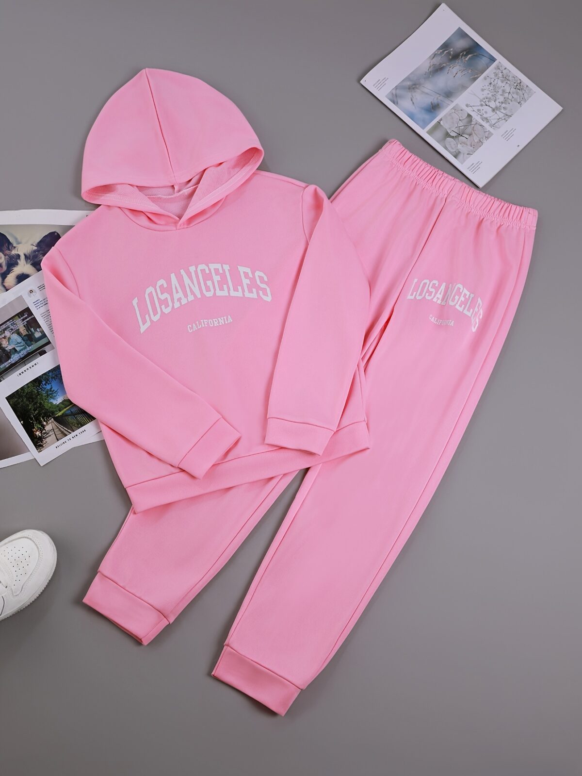 Adorable girl wearing a playful spring hues hooded sports suit featuring a charming cartoon print Perfect for spring adventures