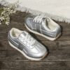 Stylish silvery gray and white low top sneakers for kids featuring a durable TPR sole breathable lining and secure lace up closure Perfect for everyday wear