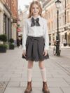 A charming little girl in a classic schoolgirl outfit smiling and playful Newness