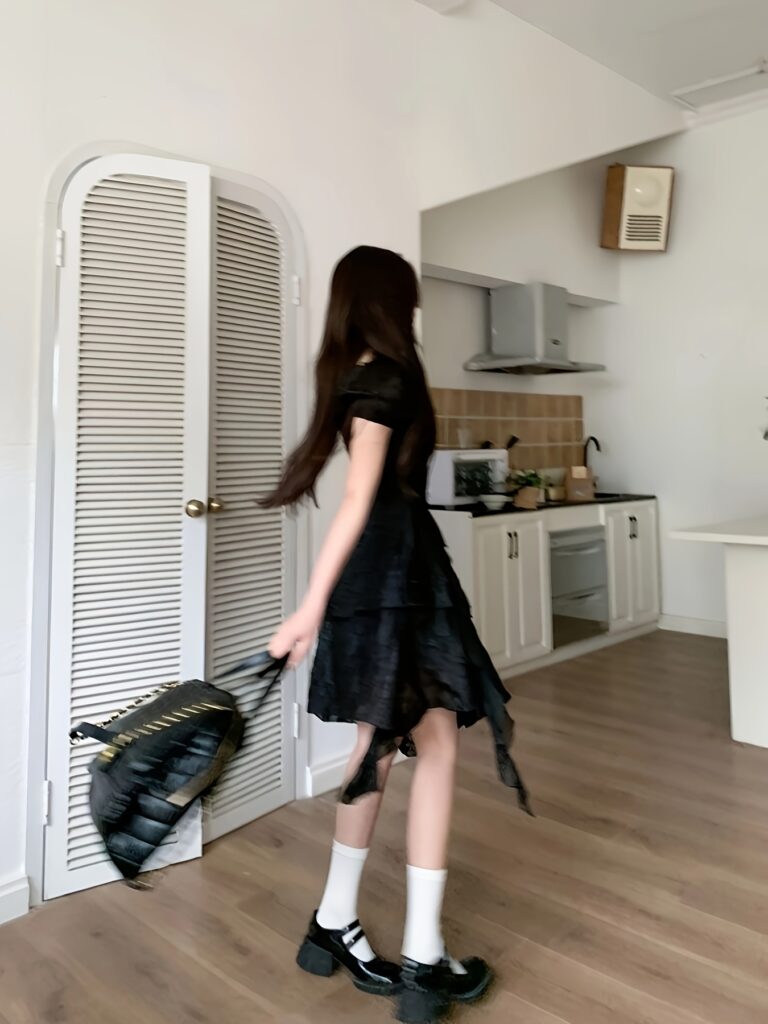 Model wearing a timeless Parisian black ruffle midi dress, showcasing its elegant silhouette and ruffle details.